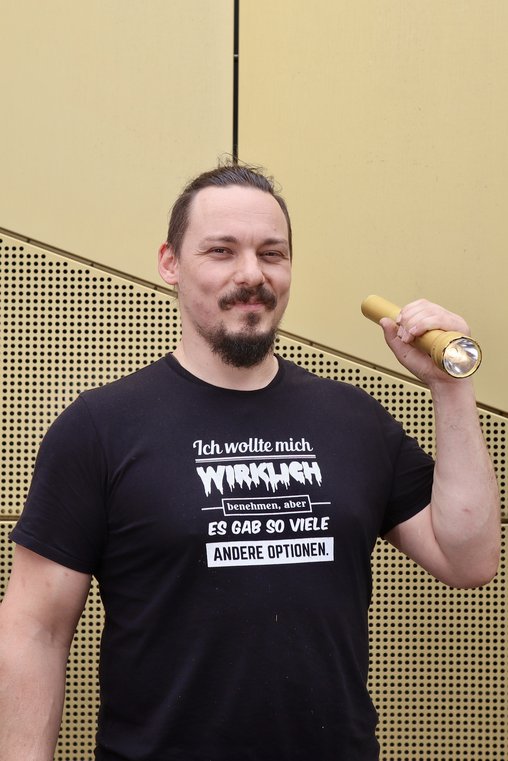 Porträt von Hannes Hirschmann mit goldener Taschenlampe vor der Theaterfassade