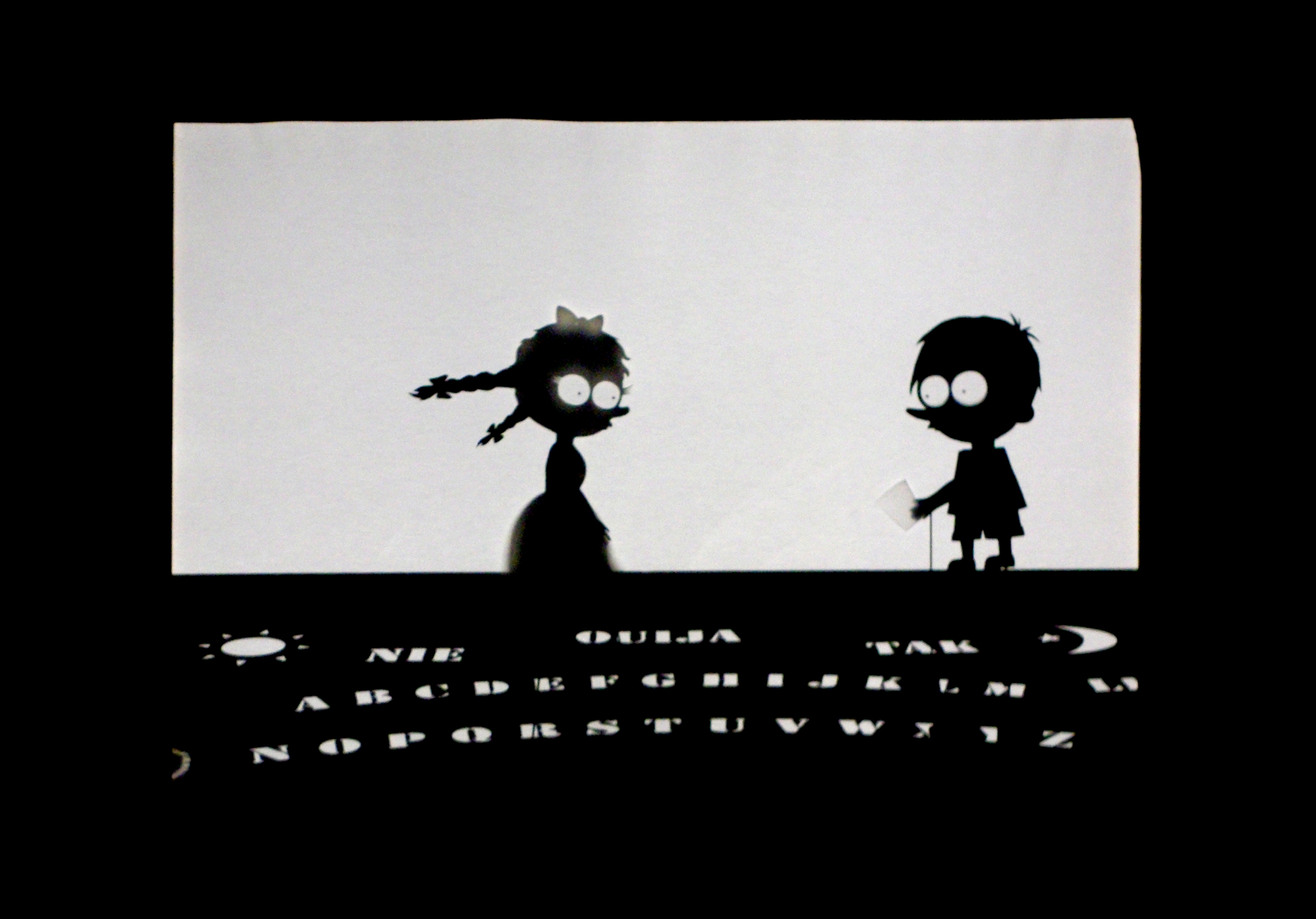 Schatten zweier scherenschnittartiger Figuren, ein Mädchen und ein Junge 